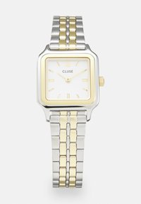 Quadratische Cluse-Uhr mit weißem Zifferblatt, goldenen und silbernen Akzenten sowie einem Bicolor-Armband mit wechselnden goldenen und silbernen Gliedern.