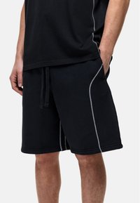 Pantaloni corti neri in cotone con vita con cordino, caratterizzati da cuciture grigie chiare lungo i lati e due tasche laterali.