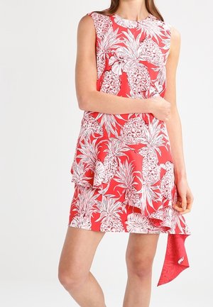 Czerwona sukienka bez rękawów z białym nadrukiem ananasów i liści, z warstwowymi falbanami i asymetrycznym dołem zwisającym z jednej strony.