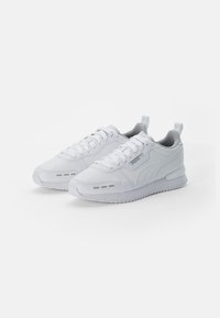 White athletic sneakers with a smooth synthetic upper, rounded toe, textured accents, and a cushioned sole. Features lace-up design and pull tab.