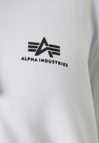 Witte sweatshirt met zwart logo met een hoekig ontwerp en horizontale strepen, gemaakt van zachte katoen.