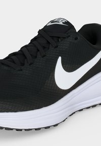 Μαύρο αθλητικό παπούτσι Nike με λευκό λογότυπο Swoosh, μαύρα κορδόνια, επενδυμένο γιακά και λευκή απορροφητική σόλα.