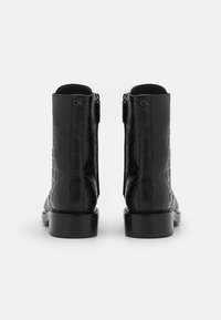 Black leather ankle boots featuring a textured pattern, smooth finish, and a low block heel, with a zipper closure on the side.