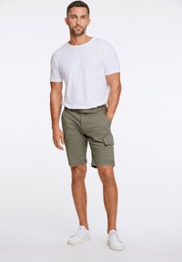 Lättviktig vit bomull T-shirt i kombination med olivgröna cargoshorts med fickor och bältesöglor, kompletterad med vita sneakers.