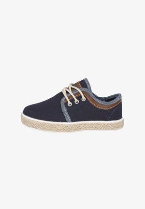 Zapatilla de lona navy con cordones beige, suela de yute trenzado y acentos de cuero en contraste en el lateral. Punta redondeada y diseño de corte bajo.