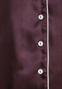 Burgundy satin fabric with a smooth texture, featuring white piping and five white buttons along the placket.