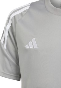 Maglietta sportiva grigia con strisce bianche sulle spalle, colletto rotondo e logo bianco ricamato sul lato sinistro. Realizzata in tessuto morbido.