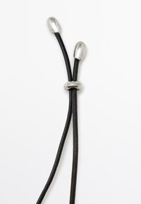 Cordon en cuir noir avec extrémités métalliques argentées et un accent circulaire central en argent gravé "Massimo Dutti." Design épuré et minimaliste.