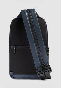 Blauwe stoffen rugzak met een getextureerd zwart paneel, gladde lederen accenten, ritssluiting en verstelbare riem. Inclusief een voorvak.