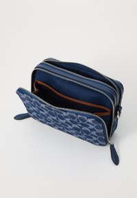 Portafoglio blu con zip, esterno in denim a motivo, dettagli in pelle e molteplici scomparti. Presenta accessori in argento e tasche interne.