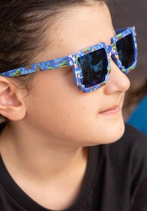 Lunettes de soleil bleues avec une monture géométrique, présentant des motifs colorés en pixels. Verres sombres avec une qualité réfléchissante.