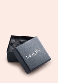 Svart texturerad smyckesbox med inskriptionen "Sofia Milani Jewels", delvis öppen, vilket avslöjar svart silkepapper inuti. Fyrkantig form.