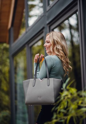 Graue Tasche aus glattem synthetischem Material, mit einem V-förmigen Designelement, zwei schwarzen Griffen und einem dezenten Logo auf der Vorderseite.