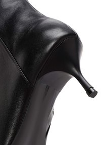 Zapato de tacón alto de cuero negro con una silueta elegante, punta afilada y un tacón negro brillante que acentúa su diseño aerodinámico.