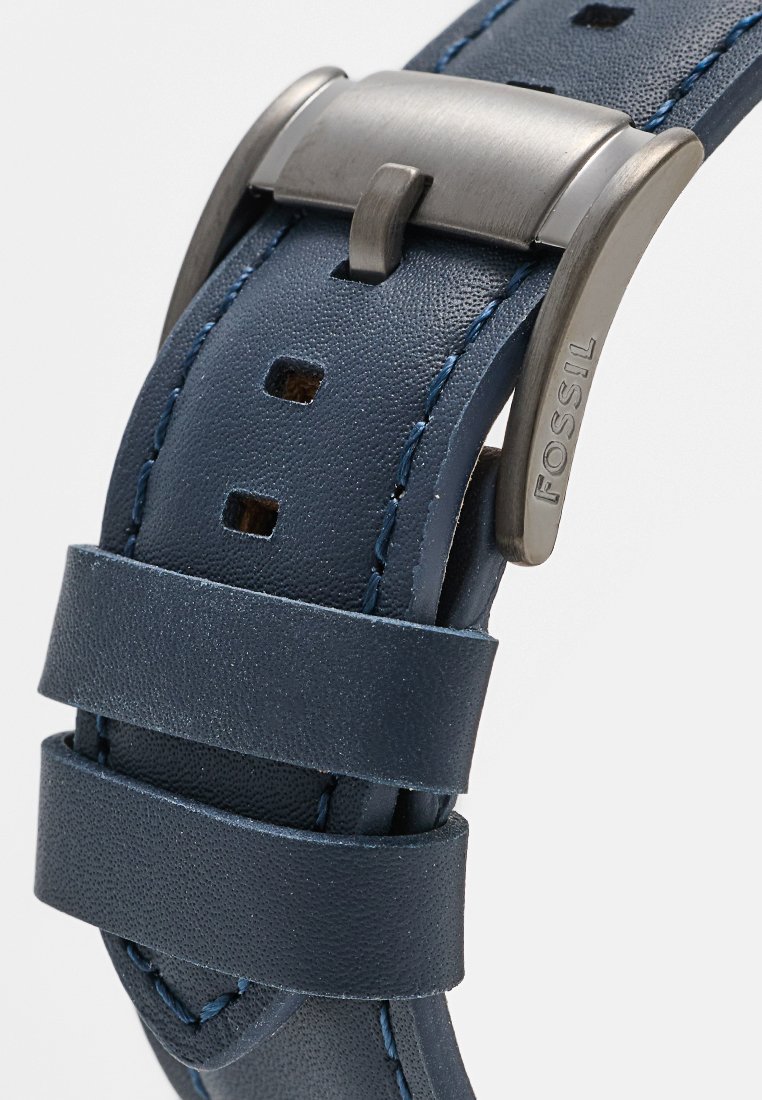 Bracelet de montre en cuir marine avec finition texturée, dotée de coutures bleu contrastantes, d'une boucle en métal argenté et de plusieurs trous d'ajustement.