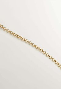 Cadena de metal dorado con eslabones ovalados y circulares alternos; textura suave y acabado brillante, colocada plana sobre un fondo claro.