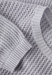 Maglione in lavanda chiaro lavorato a maglia con un design a rete aperta. Maniche a costine e scollatura, con una texture morbida e schemi di punto visibili.