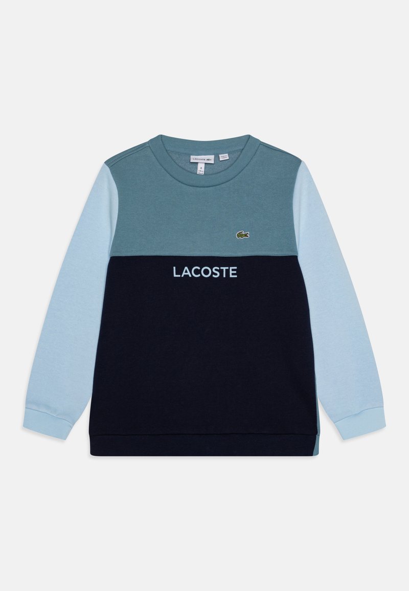 Sweatshirt coloré en blocs de bleu marine, bleu clair et turquoise, avec un col rond, un logo Lacoste brodé et des poignets côtelés.