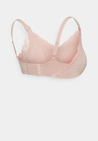 Reggiseno rosa chiaro rifinito in pizzo con spalline regolabili e chiusura a tre file di ganci su sfondo bianco semplice.