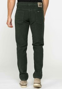 Pantaloni in cotone verde scuro con etichetta in vita, tasche posteriori e design slim fit. Texture liscia, senza motivi o decorazioni visibili.