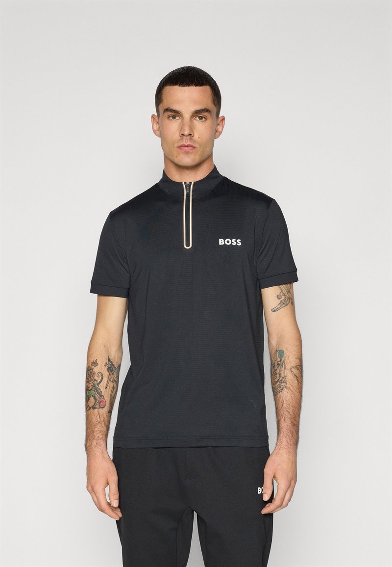 Kort zip-up, svart polo shirt med krage, som har den vita "BOSS"-logotypen på vänster bröst och en texturerad tyg.