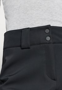 Μαύρο παντελόνι με λεία υφή, διαθέτει επίπεδη μέση, δύο μαύρα κουμπιά και στενή εφαρμογή. Συνοδεύεται από γκρι κορυφή.