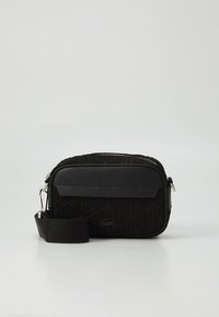 Črna pravokotna torbica čez ramo z geometričnim vtisnjenim vzorcem. Ima usnjen pas in poudarke z logotipom, zadrgo na zapiranje ter gladek zaključek.