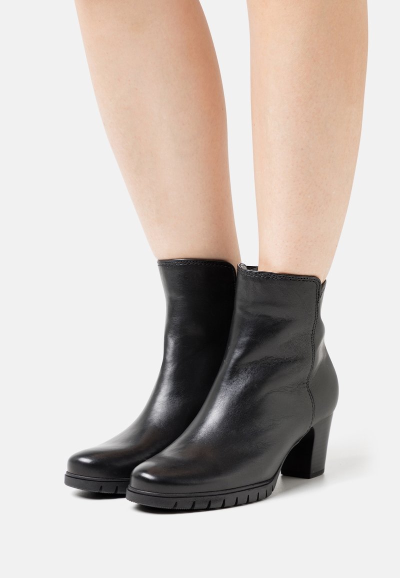 Bottines en cuir noir avec une finition lisse, des orteils ronds et un talon bloc. Elles disposent d'une fermeture éclair sur le côté et d'une semelle en caoutchouc texturé pour une meilleure adhérence.