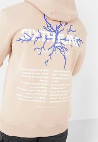 Felpa pesca con una grafica di un albero blu e testo bianco. La parte posteriore presenta frasi sulla moda streetwear e include la data "6 GIUGNO 2008."