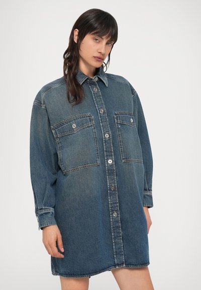 Φόρεμα πουκάμισο από denim σε σκούρο μπλε, με κούμπωμα μπροστά με κουμπιά, δύο τσέπες στο στήθος και μακριά μανίκια με γυρισμένα μανσέτες. Απαλή υφή.