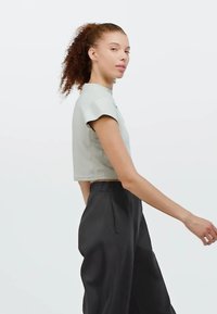 Heledhalli, lühikeste varrukatega lühike topp, millele on lisatud mustad, vabalt istuvad püksid. Sujuv tekstuur, minimalistlik disain.