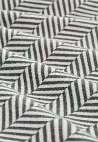 Textiel met een visgraatpatroon met afwisselend zwarte en witte strepen, met een zachte, textuurrijke oppervlakte.
