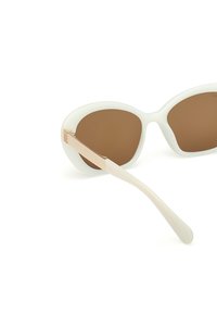 Białe, oversize okulary przeciwsłoneczne z brązowymi soczewkami, elegancka plastikowa oprawka i złote akcenty na zauszniku, charakteryzujące się gładkim, błyszczącym wykończeniem.