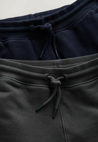 Dvi laisvalaikio kelnių poros, viena tamsiai mėlyna, kita tamsiai pilka, su gofruotomis juosmens juostelėmis, raišteliais ir minkšta tekstūra.