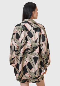 Blusa nera con una stampa botanica nei toni del verde, rosa e bianco. Tessuto morbido e testurizzato con una vestibilità rilassata e maniche lunghe.