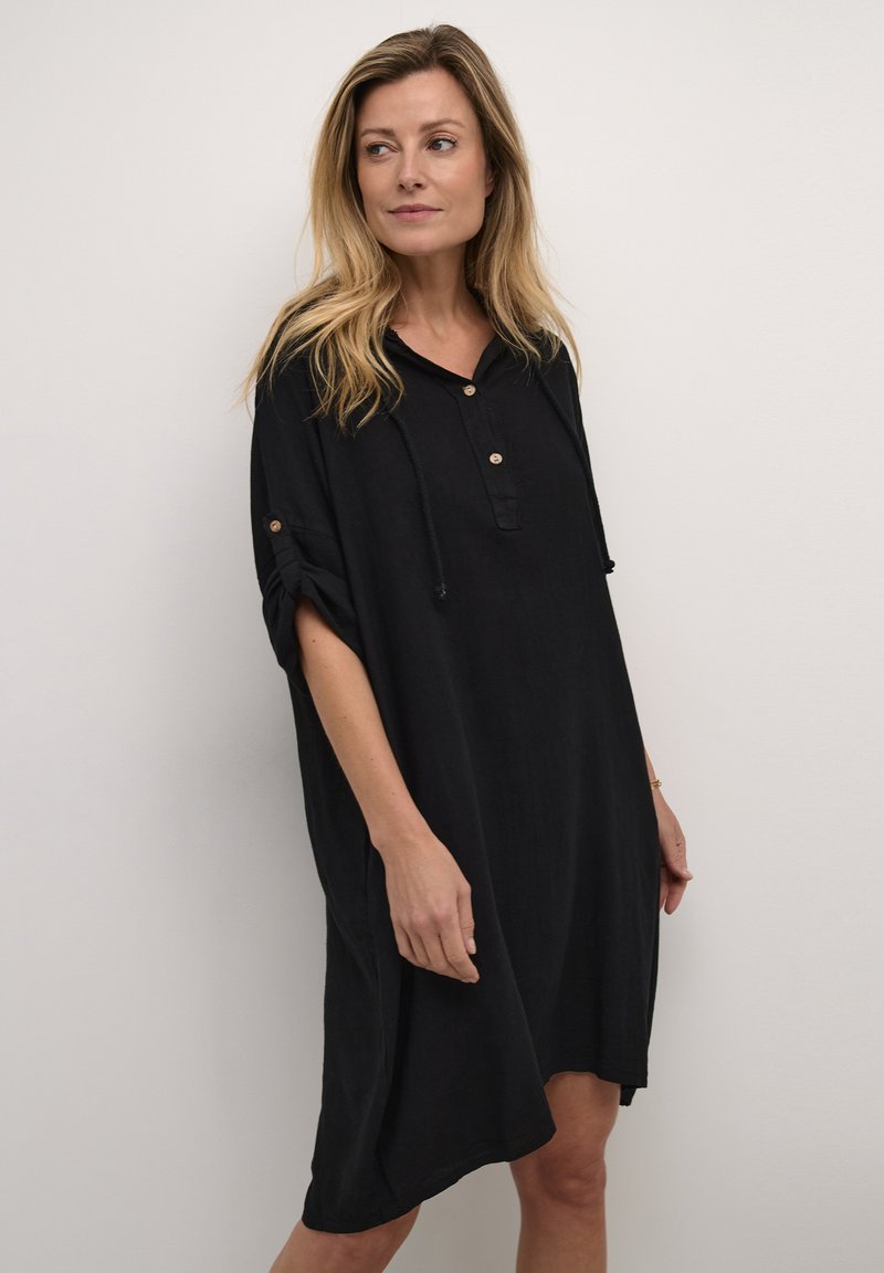 Rochie din in negru, cu o croială lejeră, mâneci scurte, glugă, deschidere cu nasturi și mâneci răsfrânte. Textură netedă și design până la genunchi.