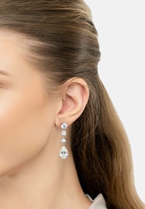 Drop earrings featuring clear, faceted gemstones in various shapes, including a large teardrop, with a shiny silver setting.