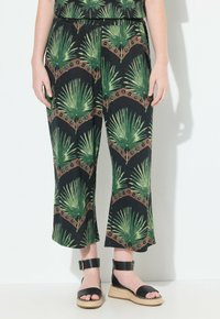 Zwarte, wijde broek met een groen palmbladpatroon. Gemaakt van een zachte stof, met een elastische tailleband en een casual pasvorm.