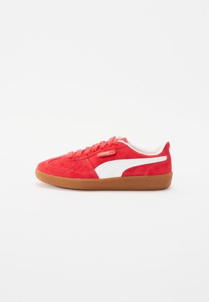 Roter Wildleder-Puma-Sneaker mit weißem Seitenstreifen und hellbrauner Gummisohle, von der Außenseite vor weißem Hintergrund betrachtet.