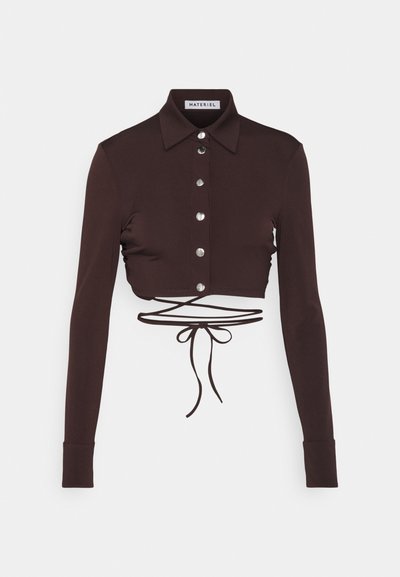 Brown cropped long-sleeve shirt with a collar, featuring silver buttons and a tie detail at the waist. Smooth fabric with a fitted design.