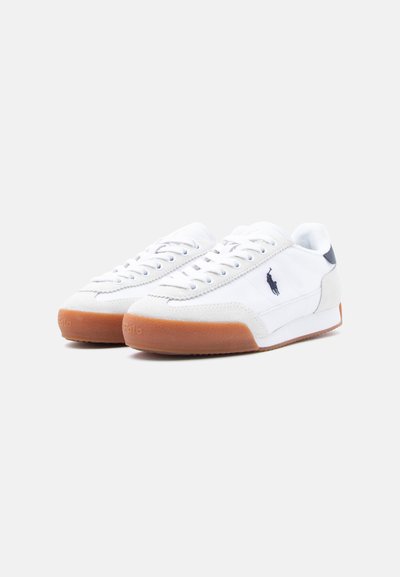 Hvite lær-sneakers med såle av gummigummi og blå aksenter. Har snøring og brodert logo på siden.