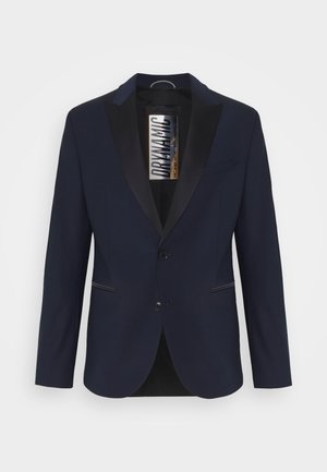 Blazer azul-marinho com lapela preta em cetim, dois botões e bolsos frontais. O tecido é suave, com um corte ajustado e detalhes mínimos.