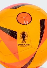 Pallone da calcio con pannelli arancioni e gialli vivaci, motivi a zigzag neri, punti neri e branding UEFA Euro 2024 vicino alla parte inferiore.
