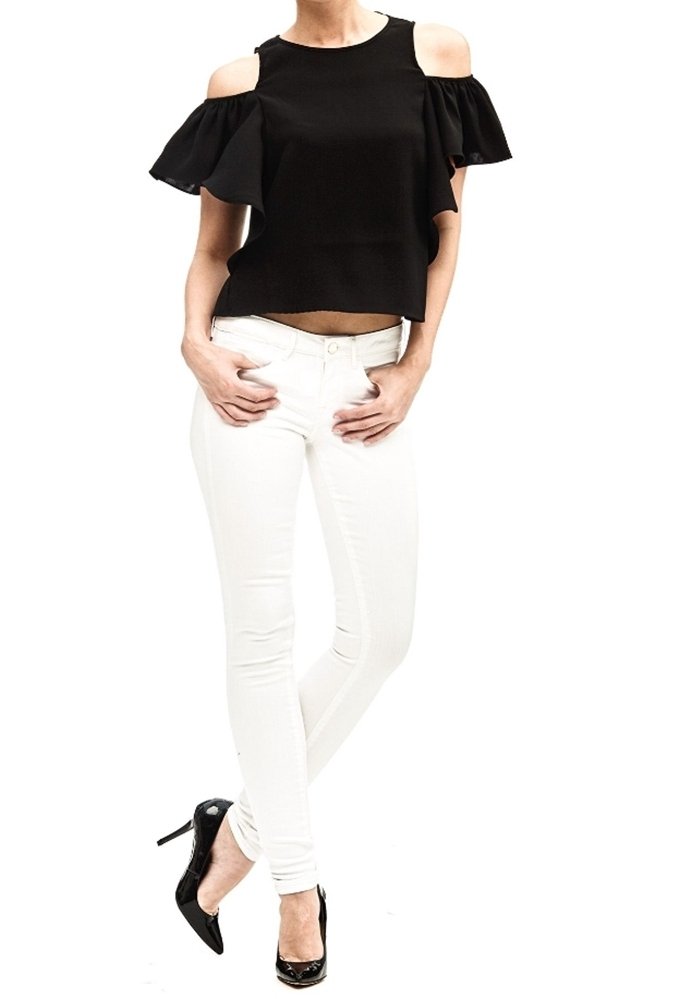 Top negro de hombros descubiertos con mangas con volantes, combinado con jeans skinny blancos. La modelo lleva zapatos de tacón negros. Diseño y ajuste simples.