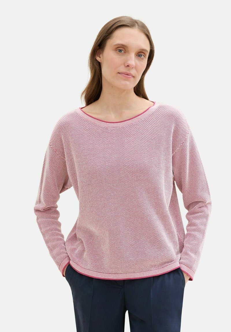 Piros és fehér mintás, hosszú ujjas póló széles nyakkal és bordás szélekkel, sötétkék nadrággal párosítva. Lazán illeszkedő és puha tapintású.