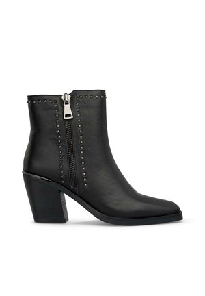 Black leather ankle boots feature a pointed toe, side zipper, studded detailing along the zipper, and a chunky block heel.