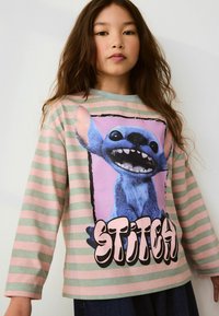 Long-sleeve striped shirt in pastel green and pink with a large Stitch graphic print and bold black text reading "STITCH" at the bottom.