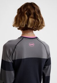 Szara i granatowa koszulka sportowa na długi rękaw z poziomymi paskami, z różowym logo i prążkowanym kołnierzykiem. Gładka faktura materiału.