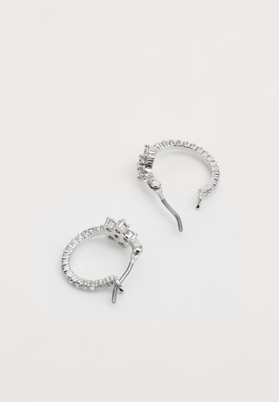 Silver hoop earrings featuring a textured design with multiple small clear gemstones along the edge and a hinged closure.