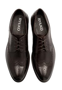 Brązowe skórzane buty z motywem wingtips, posiadające dekoracyjne perforacje i sznurowanie. Gładkie wykończenie i lekko spiczasty kształt noska.